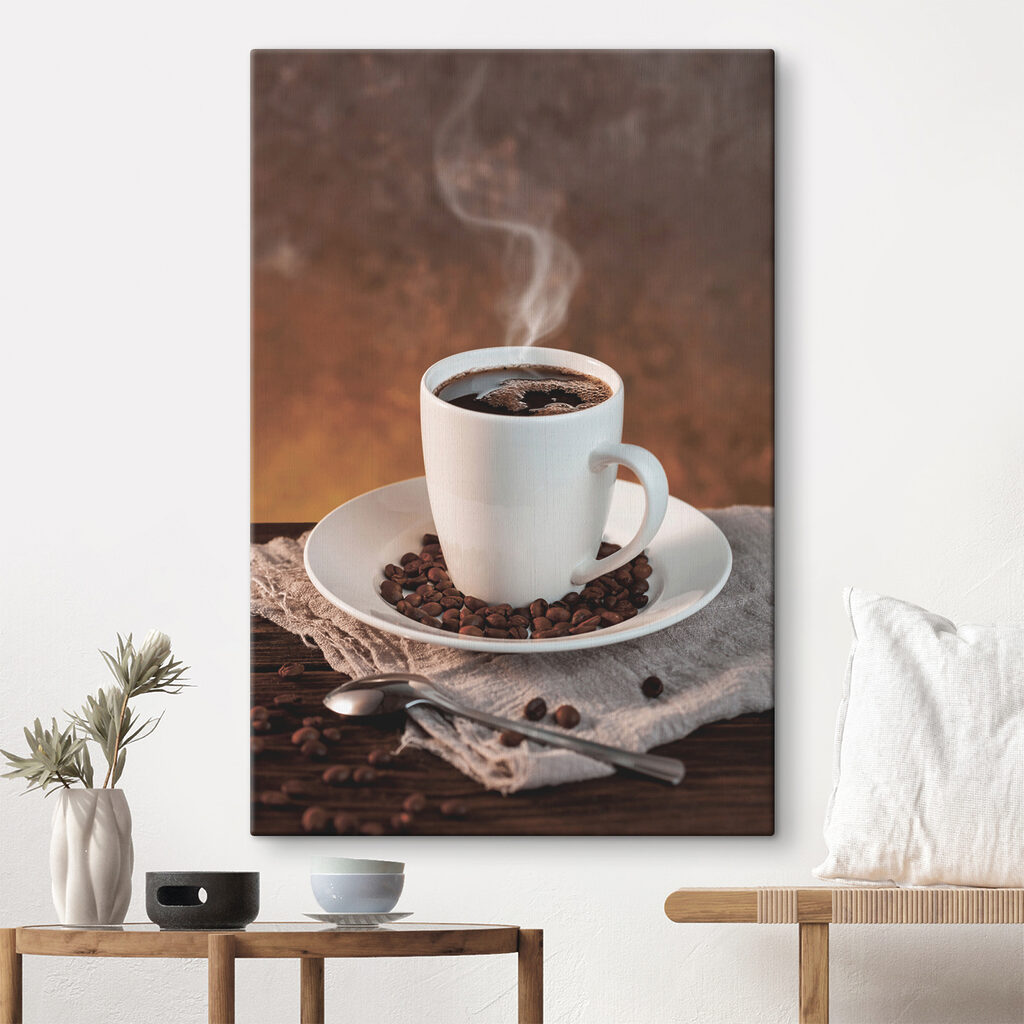 A cup of coffee on a plate with beans and a spoon