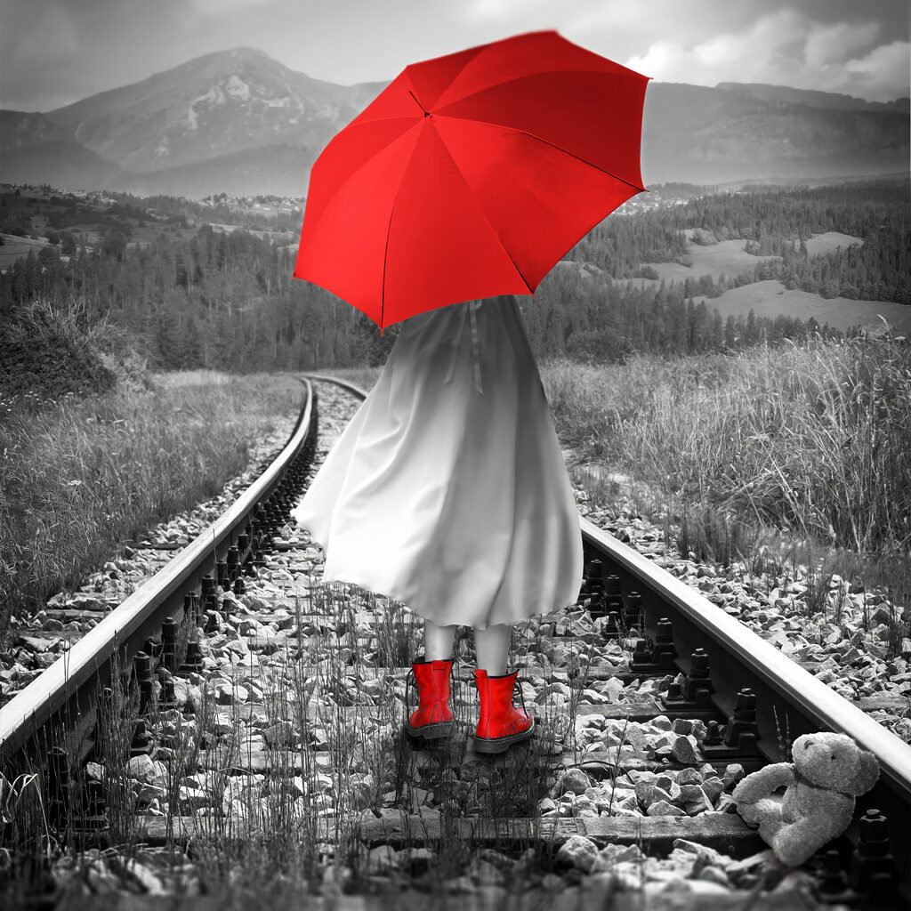 A person with a red umbrella on a train track A person with a red umbrella on a train track