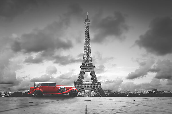 A red car parked in front of a large tower