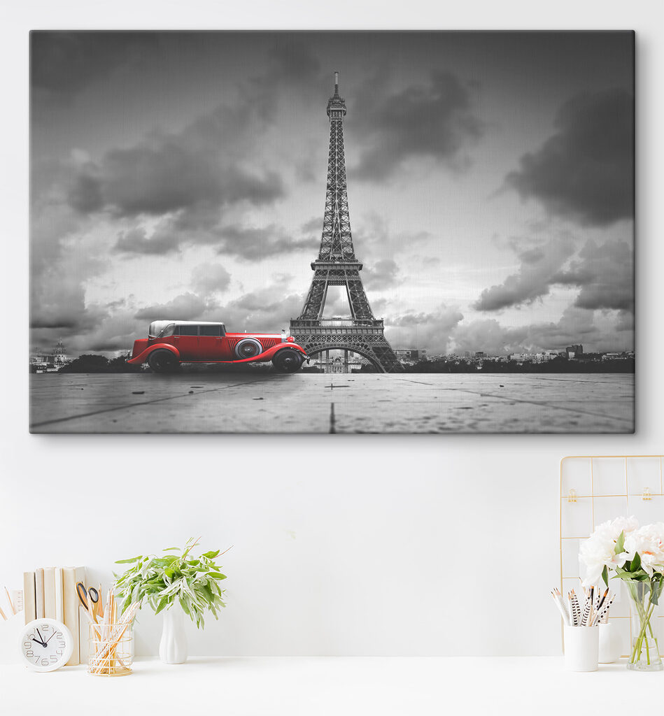 A red car parked in front of a large tower