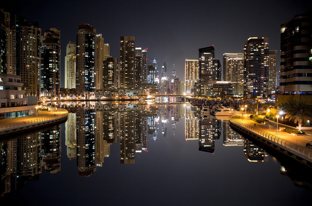 City skyline with lights reflecting on water City skyline with lights reflecting on water