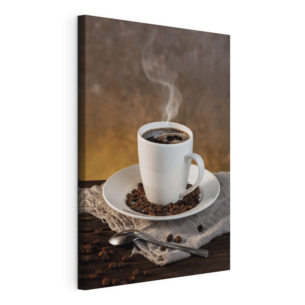 A cup of coffee on a plate with beans and a spoon